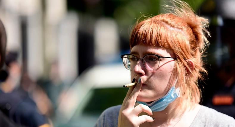 A woman wearing a protective face mask smokes a cigarette on June 7, 2020.