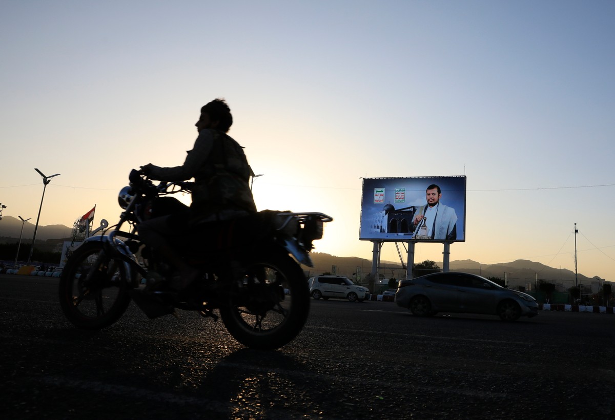 Motocyklista mija w Sanie plakat z wizerunkiem Abdula-Malika al-Houthi, przywódcy rebeliantów