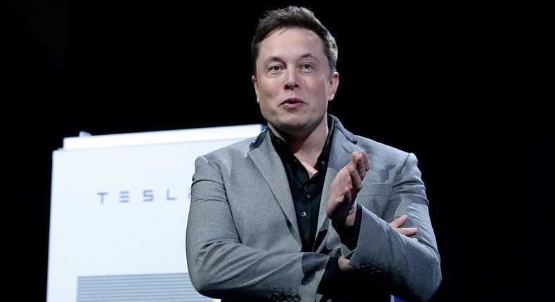 Elon Musk, CEO of Tesla, with a Powerpack unit the background unveils suit of batteries for homes, businesses, and utilities at Tesla Design Studio April 30, 2015 in Hawthorne, California
