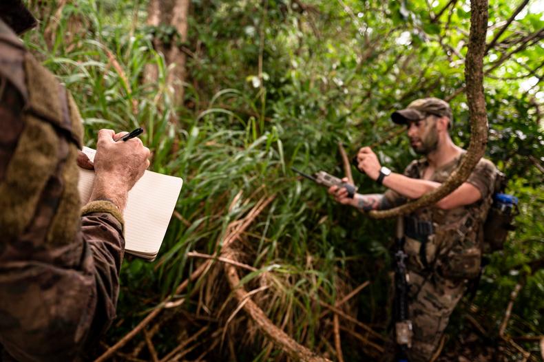 Staff Sgt. Evan Orth writes coordinates while Staff Sgt. Evan Rogowski uses a radio during a tracking exercise in Wahiawa, April 1, 2022.