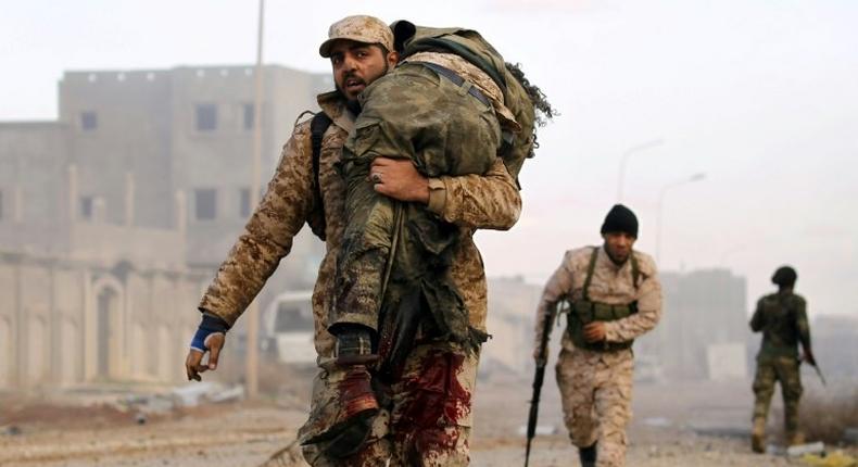 A member of the Libyan National Army (LNA) carries an injured comrade during fighting against jihadists in Qanfudah, on the southern outskirts of Benghazi