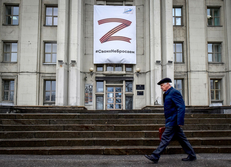 Mężczyzna przechodzi obok budynku z symbolem "Z" i hasłem o treści: "Nie rezygnujemy z naszego narodu" w Petersburgu.