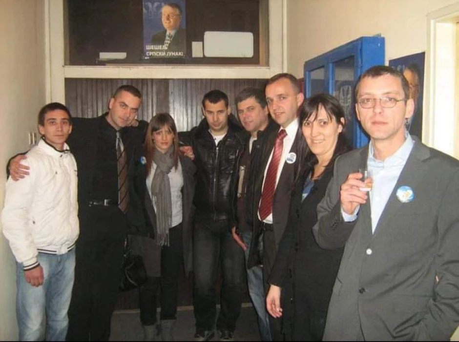 Milica Đurđević sa bedžom Vojislava Šešelja, ispod postera Vojislava Šešelja