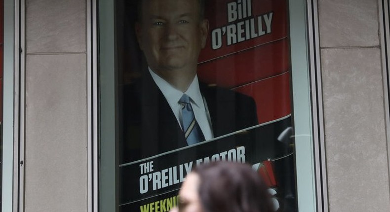 A woman walks by a sign showing Fox News Channel TV anchor Bill O'Reilly outside the News Corporation headquarters in New York City.