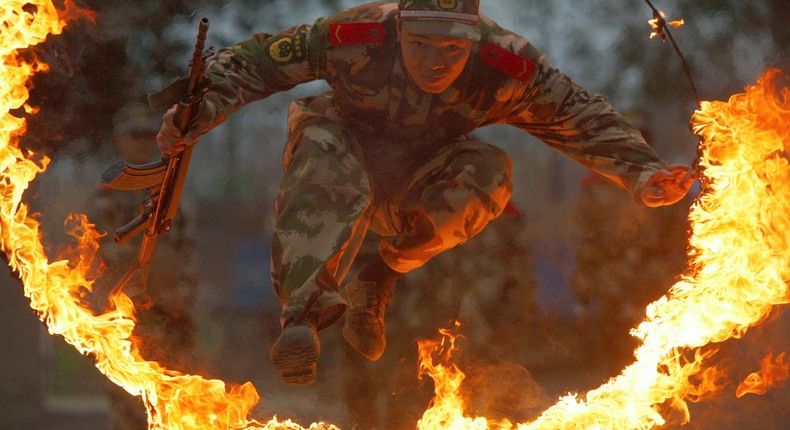 A paramilitary policeman jumps through a ring of fire during a training session at a military base in Suining, Sichuan province March 23, 2010