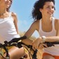 Two attractive girls on a beach with bicycles