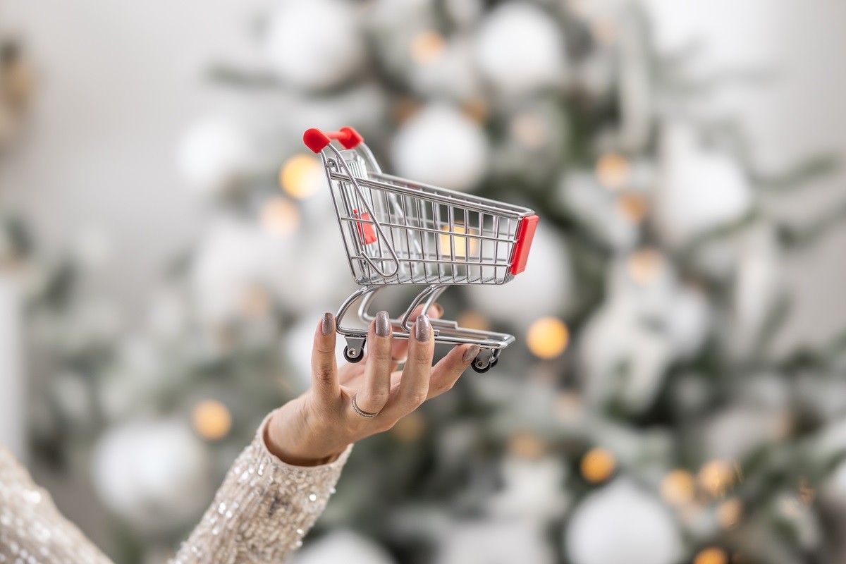 Mały wózek zakupowy na tle choinki