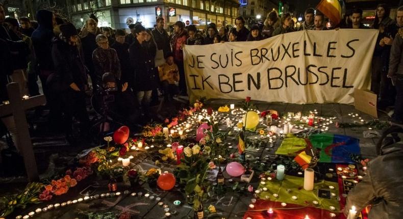 People hold a banner reading in French and Flamish I AM BRUSSELS as they gather around tributes for the victims of the Brussels bomb attacks March 22, 2016