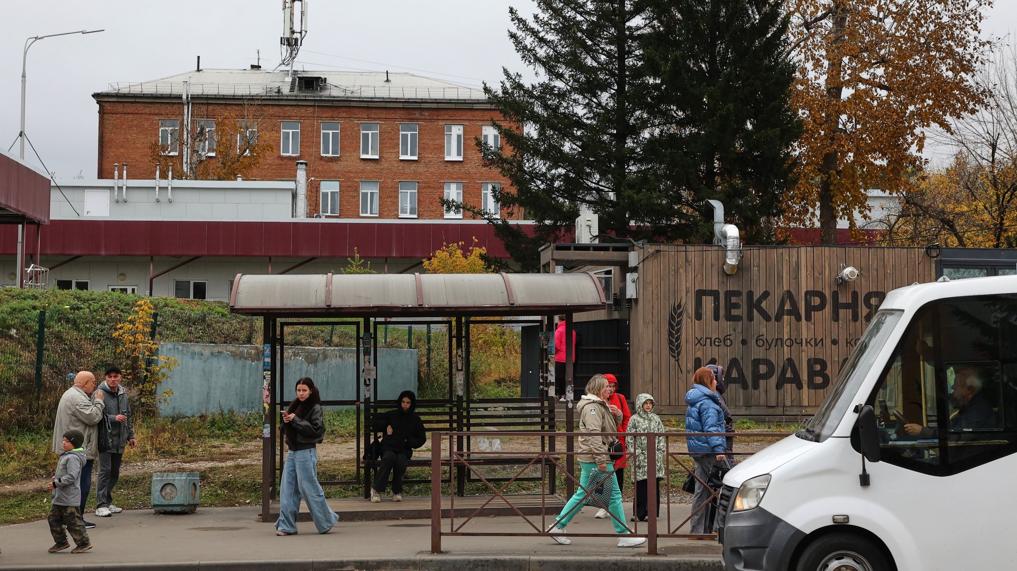 Ľudia na autobusovej zastávke v meste Šelechov. V pozadí je okresná nemocnica a zdravotnícke centrum, kde liečia infekčných choroby.