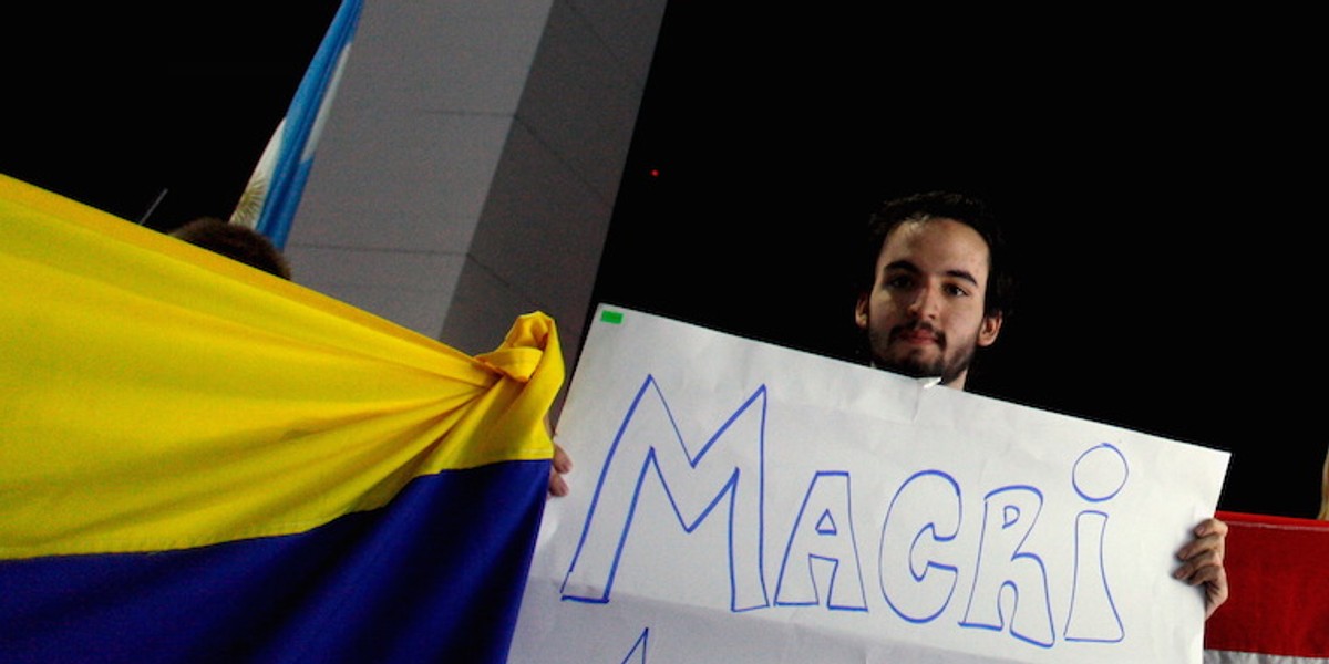 Venezuelan citizen Angel Sosa holds up a sign that reads "Macri, help Venezuela" as other supporters of presidential candidate Mauricio Macri of Cambiemos (Let's Change) celebrate in front of the Obelisk of Buenos Aires, November 22, 2015. Conservative opposition challenger Macri won Argentina's presidential election on Sunday, bringing to an end more than a decade of free-spending leftist populism with a promise to open up the ailing economy to investors.