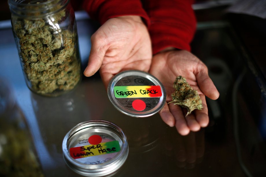 A volunteer displays jars of dried cannabis buds at the La Brea Collective medical marijuana dispensary in Los Angeles, California, March 18, 2014.