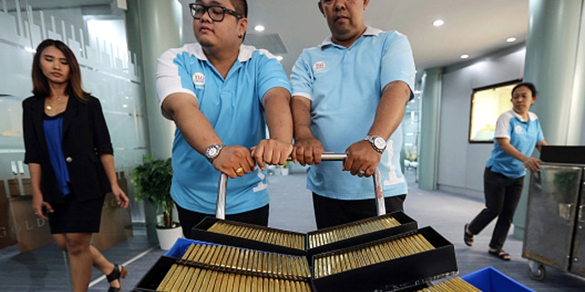 Employees push a trolley laden with crates of one kilogram gold bars at the YLG Bullion International Co. headquarters in Bangkok, Thailand.