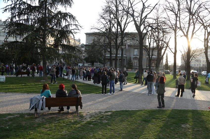 Većina okupljenih je sela na klupe u parku