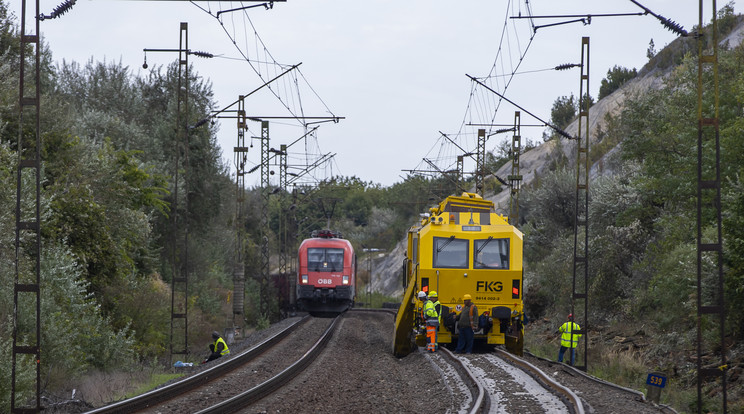 A bal vágányon, a régi síneken még járnak a vonatok, a jobboldaon dolgozó munkagép már új síenek gördülve rostáálja az ágyazatul szolgáló köveket / Fotó Czerkl Gábor