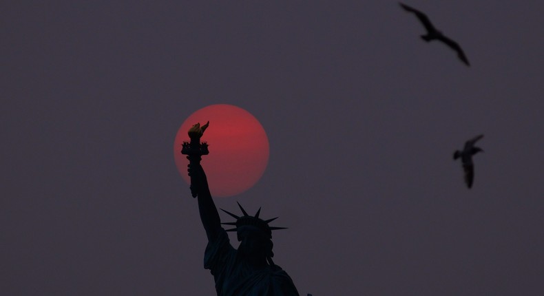 The sun is shrouded as it sets behind the Statue of Liberty in NYC in a hazy sky caused by smoke drifting into the Northeast of the US from wildfires in Canada.Gary Hershorn/Getty Images