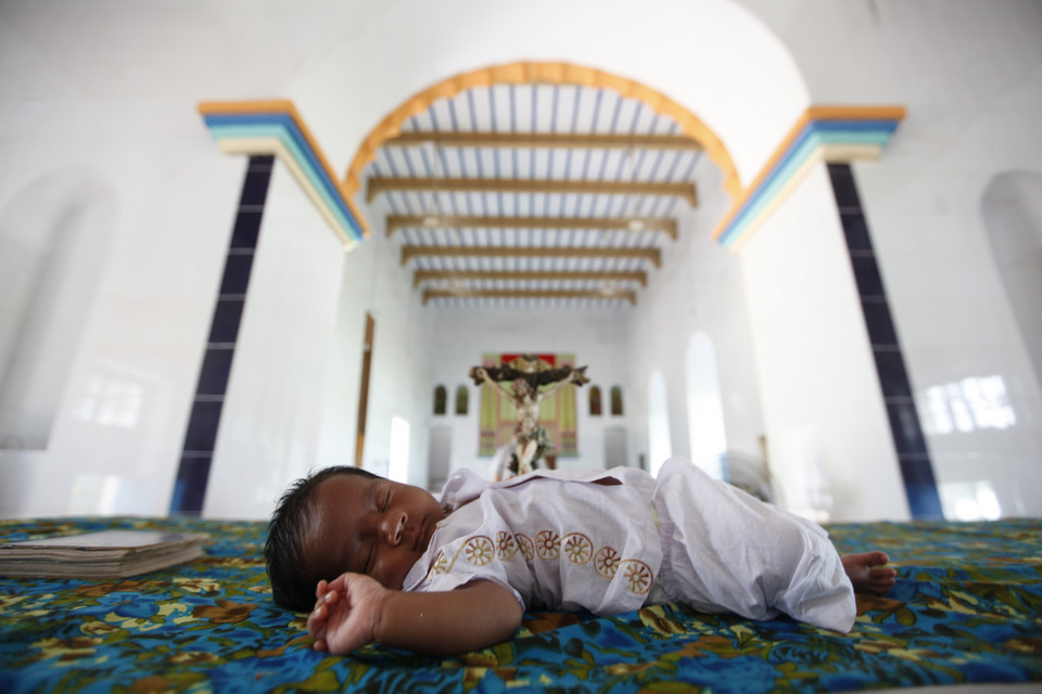 Newly baptised child, Soil Anthony Gomes, lies on the altar as his parents take photographs of him, at the Holy Rosary Church in Dhaka