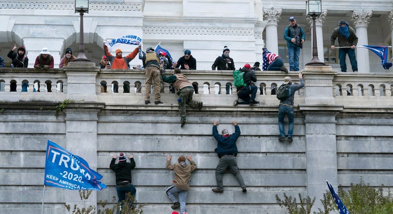 Violent insurrectionists loyal to President Donald Trump scale the west wall of the the US Capitol in Washington on January 6, 2021.