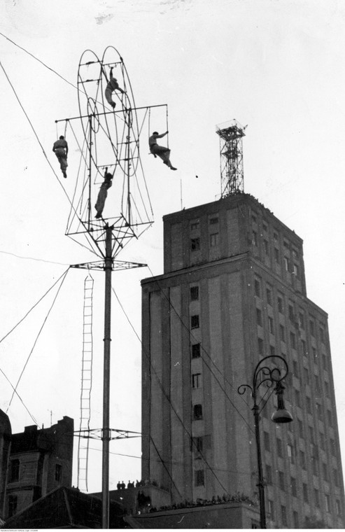 Wyczyny akrobatyczne na wysokości 36 m wykonywane na kole z rur przy pl. Napoleona. W tle budynek Prudentialu z eksperymentalną anteną telewizyjną na dachu.