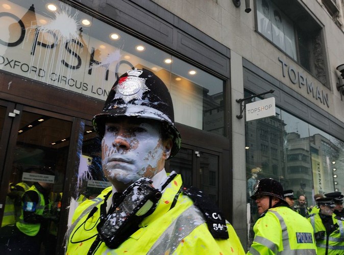 Policjant oblany farbą przed sklepem Topshop w centrum Londynu, w czasie antykryzysowego marszu; marzec 2011