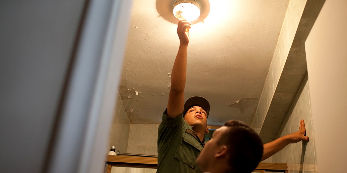 Venezuelan soldiers replace incandescent light bulbs with energy-saving bulbs in a house in Caracas March 8, 2010.