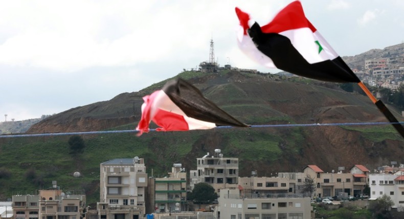 Syrian national flags are flown in a town across from the Israeli-annexed Golan Heights a day after President Donald Trump signed a proclamation declaring US recognition of the Golan as Israeli territory