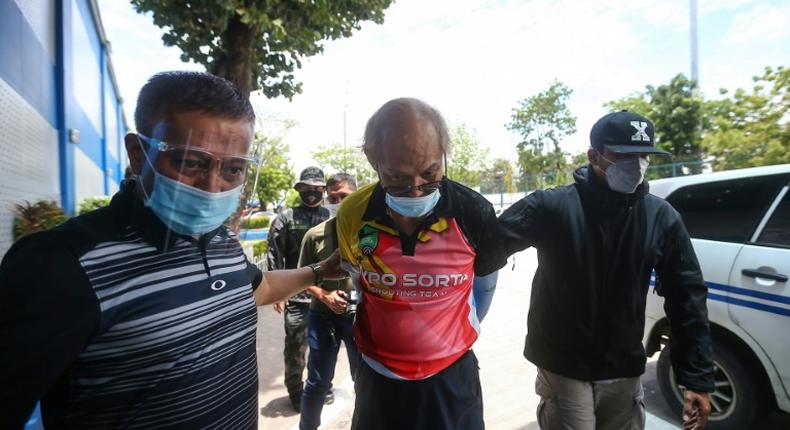 Ruben Ecleo is escorted by officers outside police regional headquarters in Manila, following his arrest