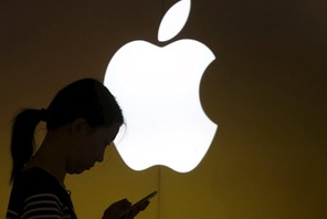 File photo of a woman looking at the screen of her mobile phone in front of an Apple logo outside an