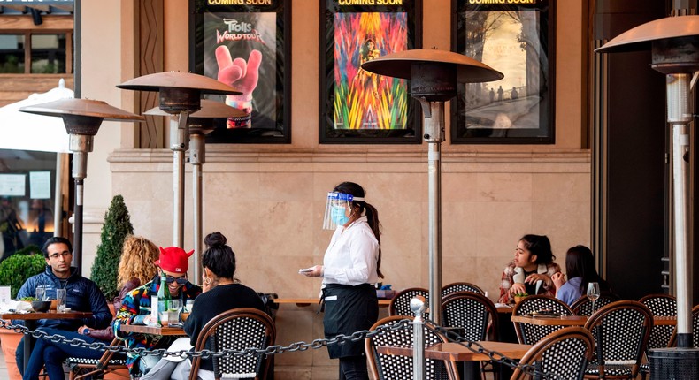 A waitress takes customers' orders in the outdoor seating area of a restaurant in Los Angeles.