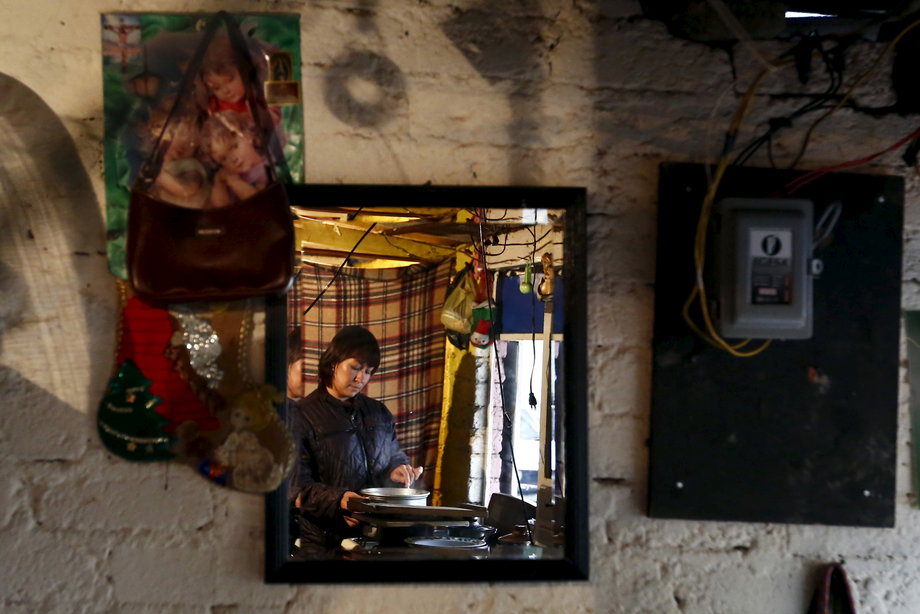 A woman cooks inside her home at Pueblo de Santa Fe neighborhood in Mexico City, July 23, 2015.