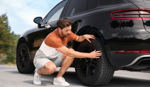 Muškarac proverava gume na vozilu