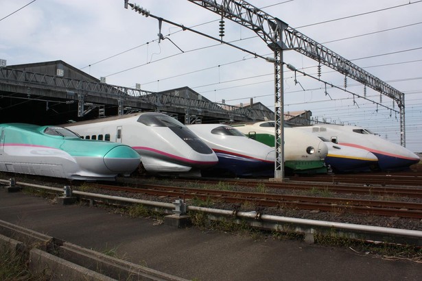 Shinkansen to nazwa japońskiej sieci kolei dużych prędkości uruchomionej w latach 60. XX w. i rozwijanej do dziś. Pierwsza linia połączyła Tokio z Osaką przed igrzyskami olimpijskimi w 1964 r. Różnorodność pociągów kursujących w ramach sieci Shinkansen jest oszałamiająca. Na zdjęciu prezentacja starszych modeli shinkansenów z okazji dnia otwartego Niigata Shinkansen Rolling Stock Center. (Zdjęcie na licencji CC BY-SA 3.0, autor: DAMASA, Wikimedia Commons).