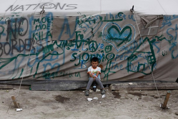 A boy sits next to a tent at a makeshift camp for refugees and migrants at the Greek-Macedonian bord