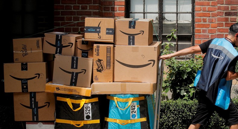 An Amazon delivery worker pulls a delivery cart full of packages during its annual Prime Day promotion in New York