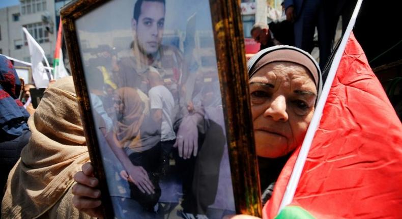 A woman holds the portrait of a Palestinian prisoner during a rally in the West Bank city of Ramallah to show support for hundreds in Israeli jails who went on hunger strike on April 17, 2017