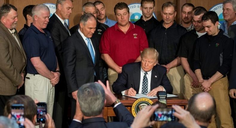 Surrounded by miners from Rosebud Mining, US President Donald Trump (C) signs the Energy Independence Executive Order at the Environmental Protection Agency (EPA) Headquarters in Washington, DC, on March 28, 2017