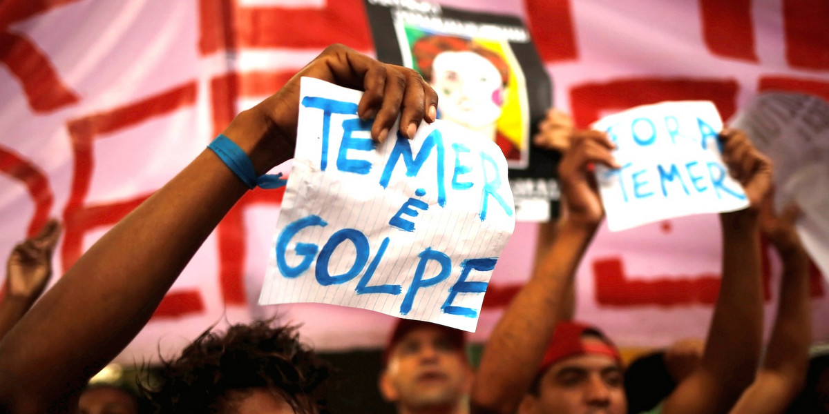 Members of Brazil's Homeless Workers' Movement (MTST) shout slogans during a protest against Brazil's interim President Michel Temer and in support of suspended President Dilma Rousseff in Sao Paulo, Brazil, May 22, 2016. The sign on the right reads "Out Temer" (R) while the one on the left accuses Temer of involvement in a coup.