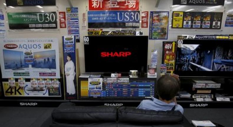 A man sitting on a sofa looks at a Sharp Corp's Aquos TV at an electronics retailer in Tokyo