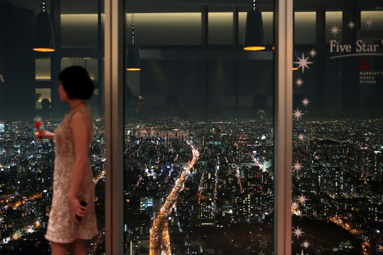 Kobieta spogląda o zmierzchu na horyzont z tarasu widokowego Abeno Harukas.