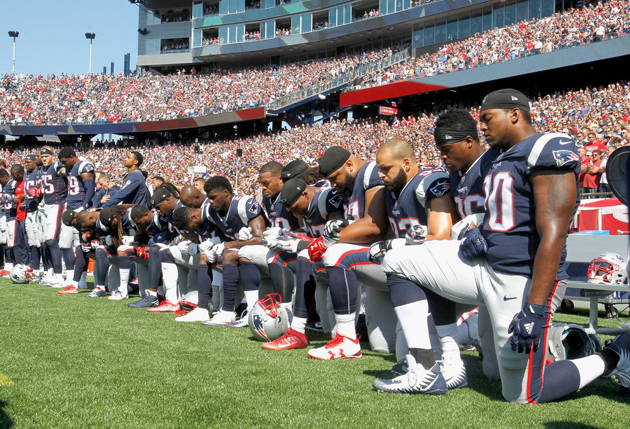 Players from the New England Patriots take a new during the national anthem.