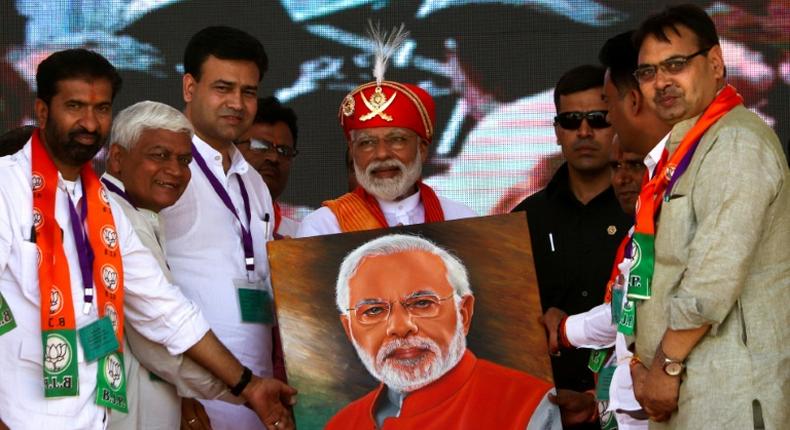 Indian Prime Minister Narendra Modi (C) holds a canvas displaying a portrait of himself during an election rally in Chittorgarh, in the western state of Rajasthan -- Modi will vote in his home state of Gujarat on Super Tuesday