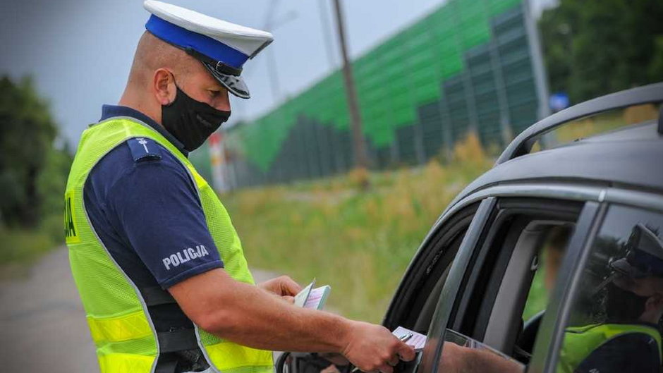 Policjant wręczający kierowcy karę za wykroczenie na drodze Źródło: Lubuska Policja/Policja.pl