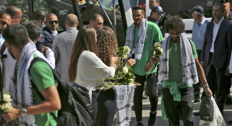 Palestinian women welcome Saudi Arabia's national football team with flowers