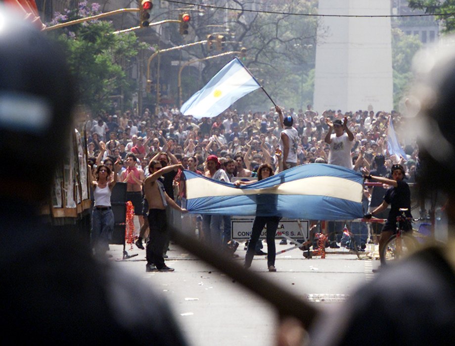 Argentine riot police watch thousands who took to the streets to demand the resignation of President Fernando de la Rua, in Buenos Aires on December 20, 2001.