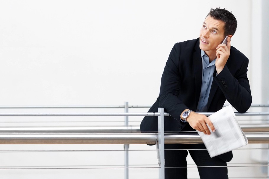 Businessman using mobile while leaning on a railing - Copyspace