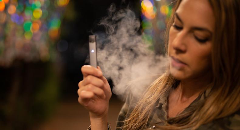 Young girl holding her juul and vaping