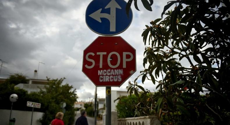 People pass by a stop sign that was vandalised with the message STOP McCann Circus in the Portuguese town of Praia da Luz where British girl Madeleine McCann disappeared 10 years ago