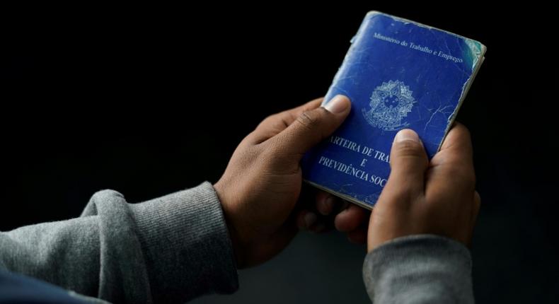 A man holds his work document at a job fair in 2019 in Rio de Janeiro, Brazil -- the country's unemployment rate has now risen to to 13.3%