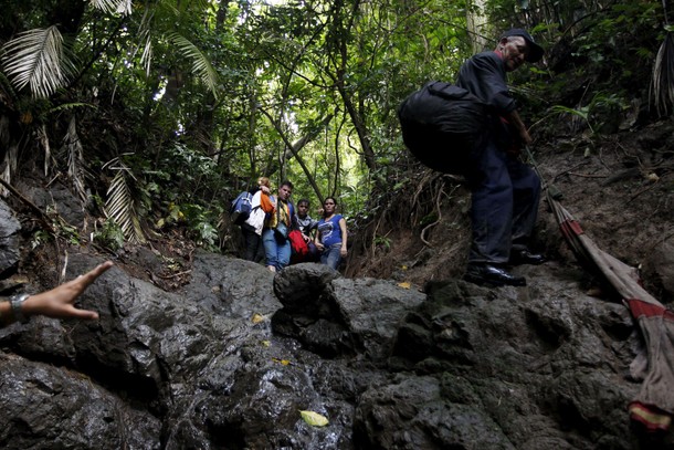 Cuban migrants look down as they cross the border from Colombia through the jungle into La Miel