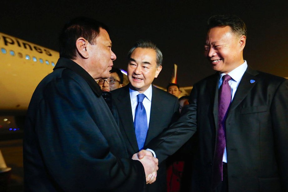 Philippine President Rodrigo Duterte shakes hands with Chinese ambassador to the Philippines Zhao Jianhua, as Chinese Foreign Minister Wang Yi looks on, at airport in Beijing.