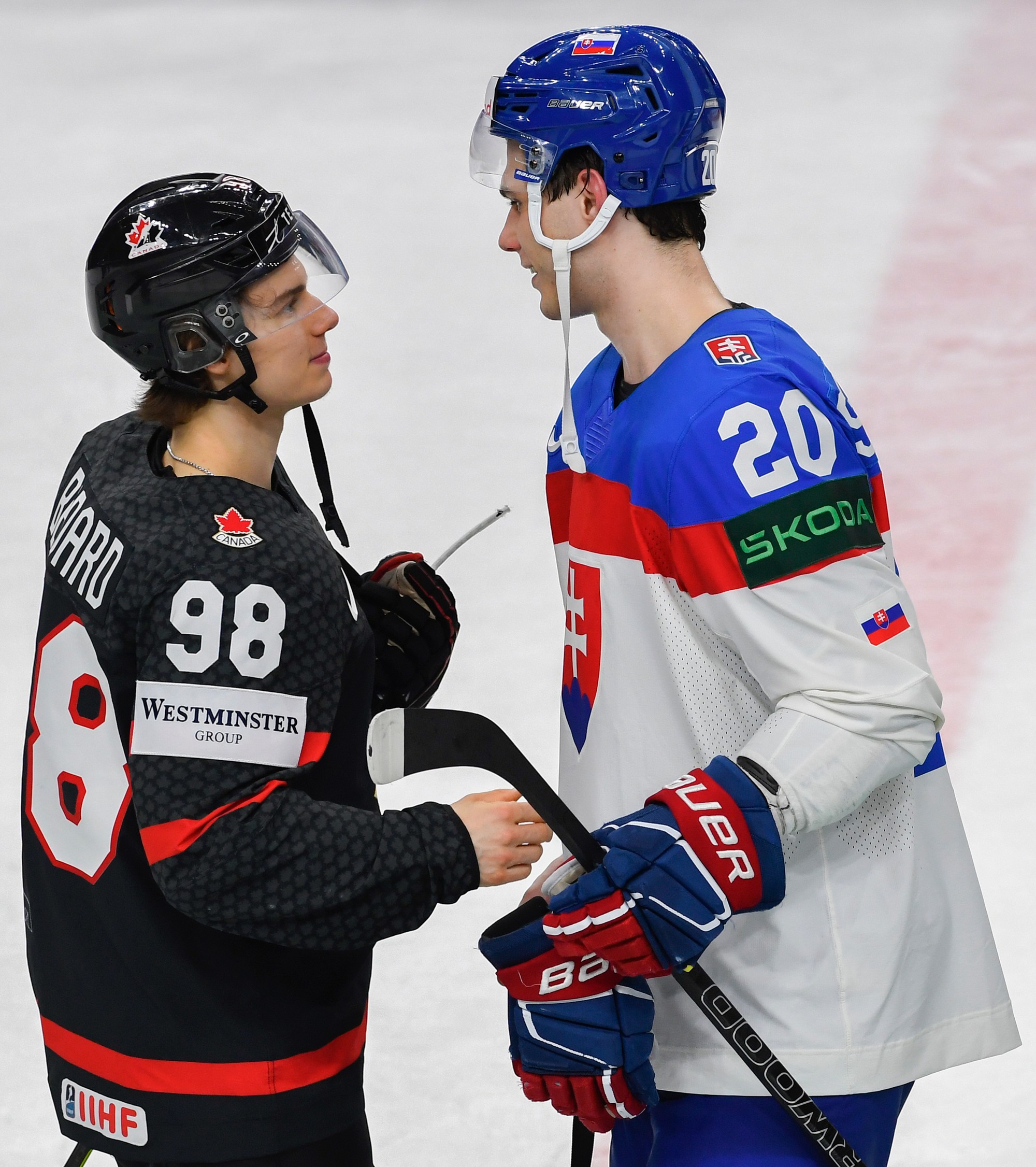 Slovenský hokejista Juraj Slafkovský a Kanaďan Connor Bedard si podávajú ruky.